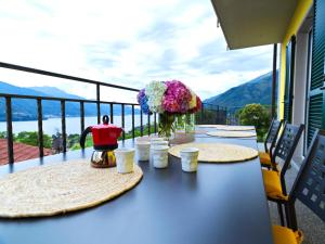 a table with two plates and flowers on a balcony at Sunny View Lake Como Apartment- Trilo in Consiglio di Rumo