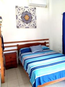 a bedroom with a bed with blue and white sheets at Portón Azul in Montañita