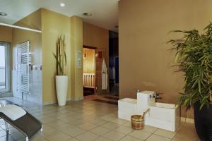 a large bathroom with two toilets and a plant at H4 Hotel Kassel City, Trademark Collection by Wyndham in Kassel