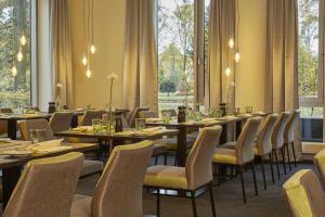 a dining room with tables and chairs and windows at Sunday Hotel Kassel in Kassel