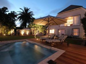 a house with a swimming pool with two chairs and an umbrella at The Gregoire Boutique Villa in Hermanus +10 photos