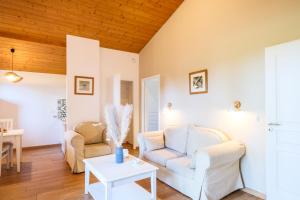 a living room with white furniture and a wooden ceiling at Résidence Pierre & Vacances Les Cottages Du Lac in Parentis-en-Born