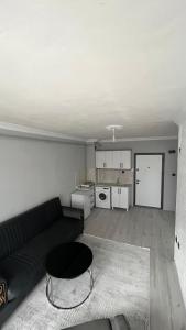 a living room with a black couch and a kitchen at Divan Kars Suit in Kars