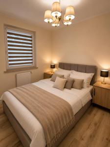 a bedroom with a large white bed with two night stands at Sportova Elegance Apartment in Płock