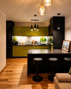 a kitchen with black and green cabinets and a counter at Sportova Elegance Apartment in Płock