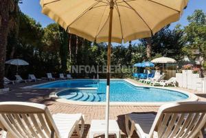 a pool with chairs and an umbrella next to it at Hotel New York in Cervia +6 photos