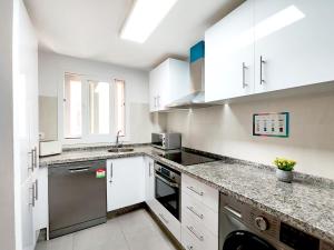 a kitchen with white cabinets and stainless steel appliances at Chill and Beach in Torremolinos