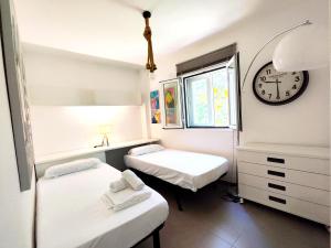 two beds in a room with a clock on the wall at Chill and Beach in Torremolinos