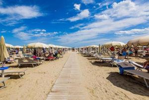 a beach with chairs and umbrellas and people on it at Hotel New York in Cervia