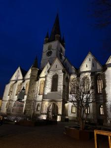 a large building with a clock tower at night at Insieme Studio - Small Square in Sibiu