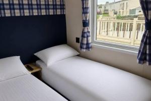 two beds sitting in a room with a window at 3 Bed - Sleeps 8 - Family & Pet Friendly in Skegness