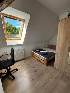 a bedroom with a bed and a window and a chair at Apartament Eden in Srebrna Góra