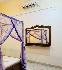 a mirror hanging on a wall with purple curtains at Pearl Resort in Arugam Bay