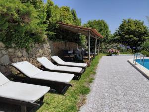 a row of chaise lounge chairs next to a pool at Porto Monte in Maceira