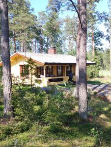 a small yellow house in the woods with trees at Lomamökki Rantaniemi in Töfsala