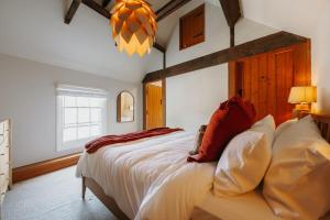 a bedroom with a bed with white sheets and red pillows at Wenlock's Cosy Cottage in Much Wenlock