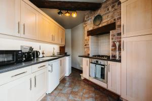 a kitchen with white cabinets and a brick wall at Wenlock's Cosy Cottage in Much Wenlock +10 photos