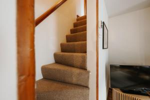 a staircase in a house with a television at Wenlock's Cosy Cottage in Much Wenlock