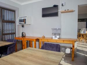 a room with a table and a tv on a wall at 5@Partridge Guesthouse in Newcastle