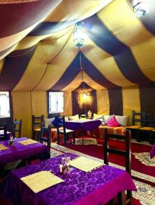 a tent with purple tables and chairs in a room at Camp Under Stars in Merzouga