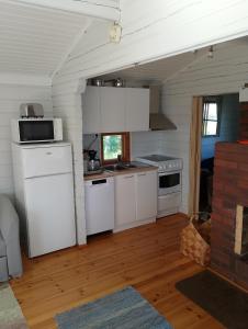 a kitchen with white appliances in a small room at Lomamökki Rantaniemi in Töfsala