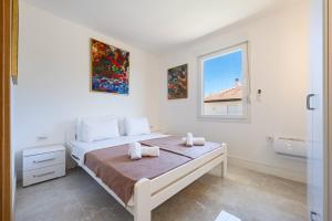 a white bedroom with a bed and a window at Barcelona Hacienda in Gostovići