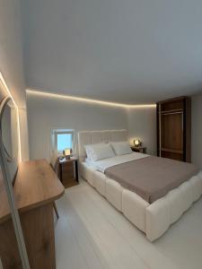 a white bedroom with a large bed and a table at Afroditi Syros in Ermoupoli