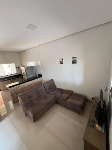 a living room with a brown couch and a kitchen at CASA para TEMPORADA in Barra do Garças