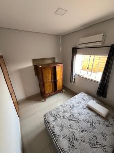 a bedroom with a bed and a dresser and a window at CASA para TEMPORADA in Barra do Garças
