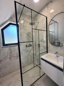 a bathroom with a glass shower and a sink at Old Mill Heritage Hotel in Ndërlysaj