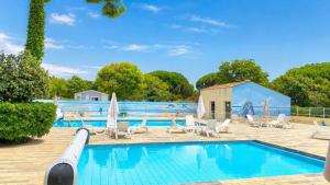 a swimming pool with chairs and umbrellas in a resort at Le Cottage D'Oléron, Mer et Animation Camping in Saint-Pierre-dʼOléron
