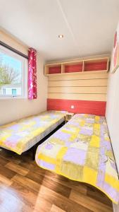 two beds in a room with a window at Le Cottage D'Oléron, Mer et Animation Camping in Saint-Pierre-dʼOléron +3 photos