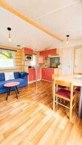 a living room with a blue couch and a table at Le Cottage D'Oléron, Mer et Animation Camping in Saint-Pierre-dʼOléron