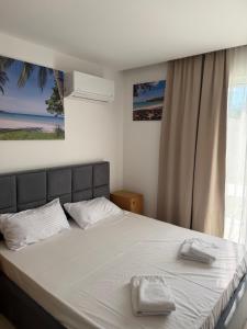 ein Schlafzimmer mit einem Bett mit weißer Bettwäsche und einem Fenster in der Unterkunft Azure Haven in Dhërmi