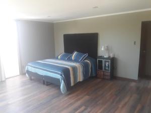 a bedroom with a bed and a wooden floor at la casa del cerro in Olmué