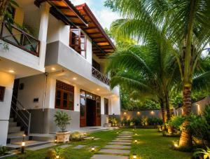 a courtyard of a house with palm trees and lights at Ceylon Stays Hiriketiya in Nilwella