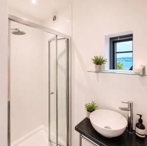 a white bathroom with a sink and a shower at 4 Bedroom Cardiff Bay View House in Cardiff +14 photos