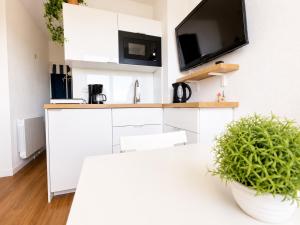 a kitchen with white cabinets and a tv on the wall at Studio - Marina 4 - 17 allée des Pinons - 5-1 in Saint-Jean-de-Monts +1 photo