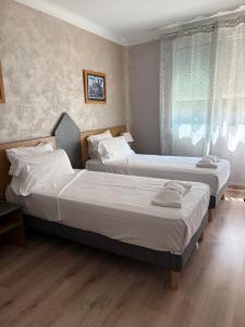 two beds in a bedroom with a window at Hotel Regina in Sète
