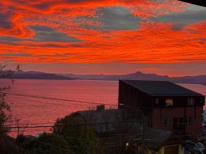 a sunset over a large body of water with a building at Olly Patagonia Suites in San Carlos de Bariloche