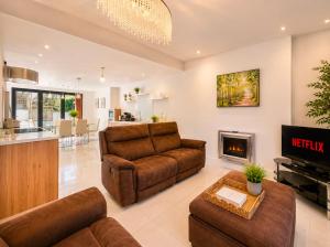 a living room with leather furniture and a fireplace at 4 Bedroom Cardiff Bay View House in Cardiff