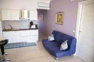 a living room with a blue couch and a kitchen at Dai Massari in Villaggio Azzurro