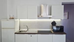 a white kitchen with a sink and a microwave at Dai Massari in Villaggio Azzurro