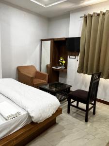 a bedroom with a bed and a chair and a table at Hotel moon palace in Maheshwar
