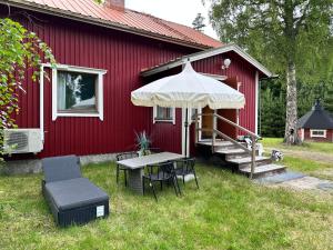 a red house with a table and chairs and an umbrella at Kodikas Mökki in Ähtäri