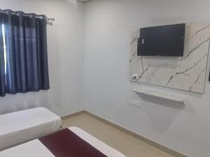 a white room with a tv on a wall at HOTEL KRISHNAM Inn in Mathura