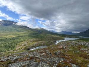 a view of a mountain with a river in the foreground at Holy Motors camp in Kvikkjokks Kapell