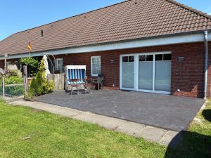 a brick house with a patio with a chair on it at Kleine Auszeit in Dagebüll