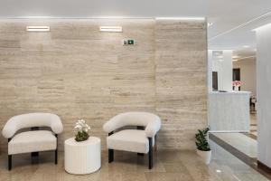 two chairs in a waiting room with a stone wall at Hotel Condor in Mamaia +58 photos