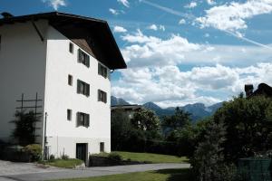 a white building with mountains in the background at Garni Renzler in Rasun di Sopra